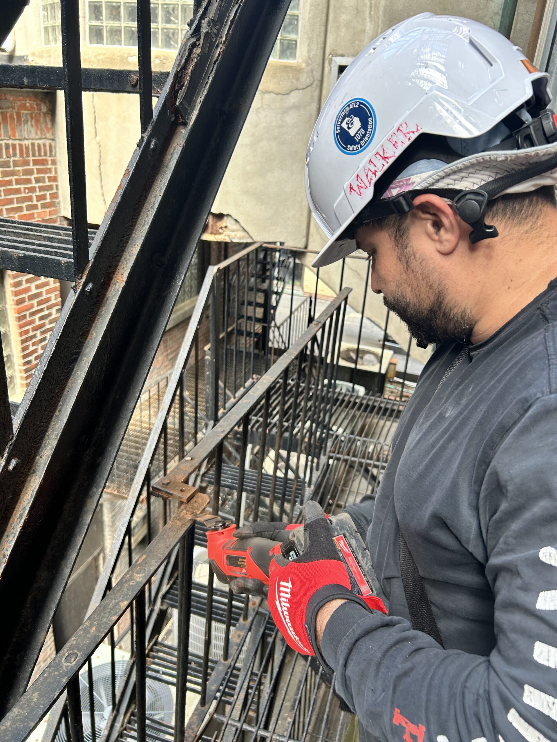 Worker using power tool on metal fire escape
