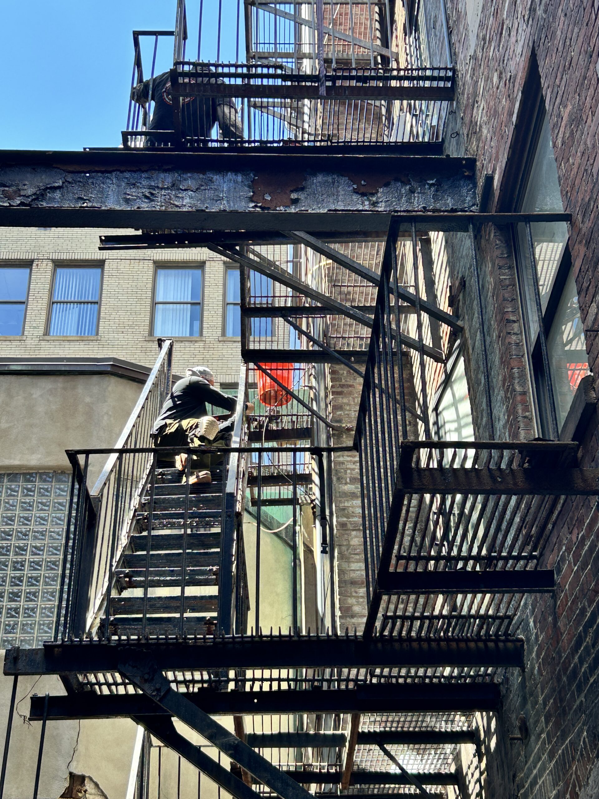 Person sitting on urban metal fire escape stairs