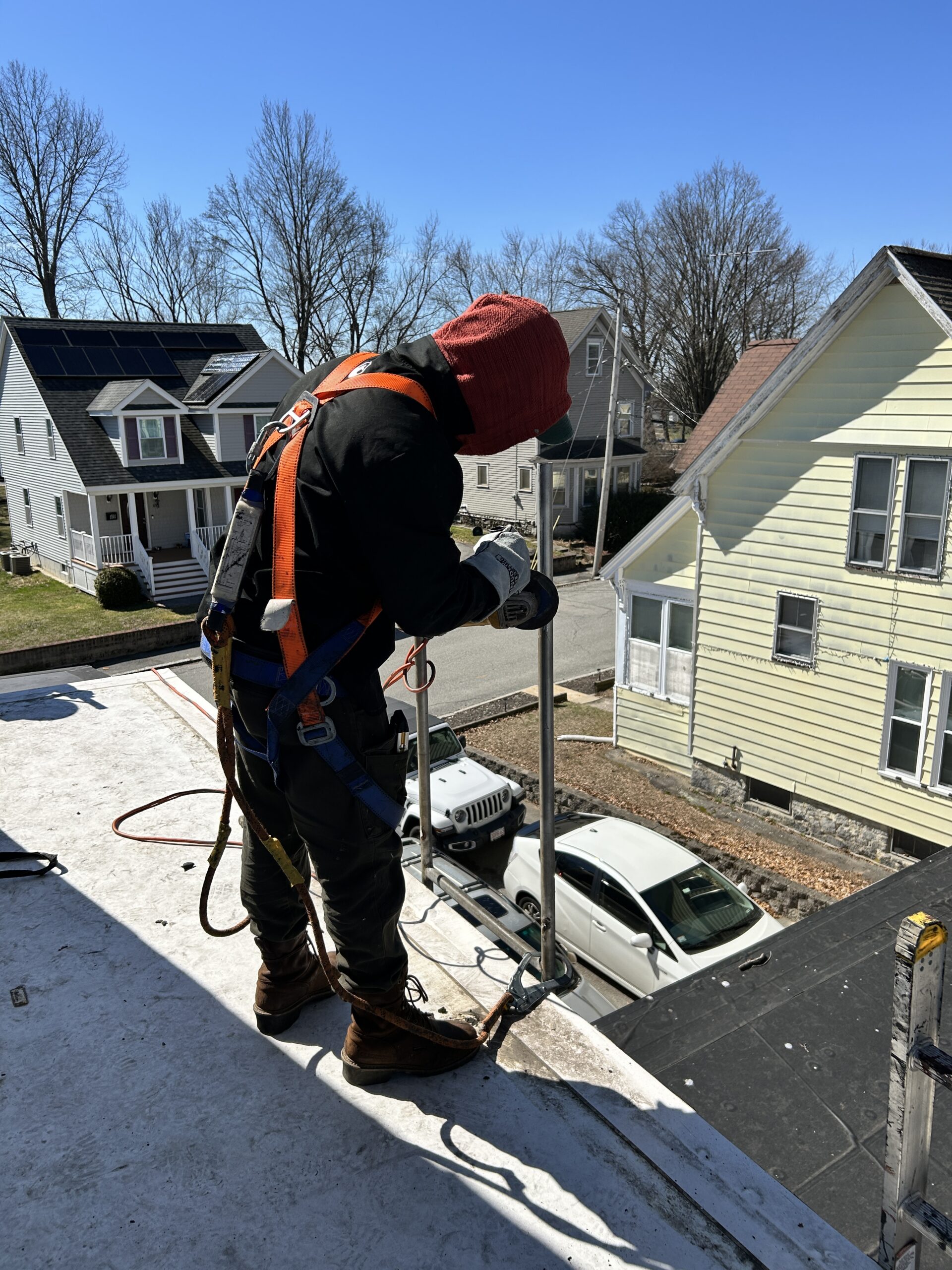 Worker in safety harness on residential roof