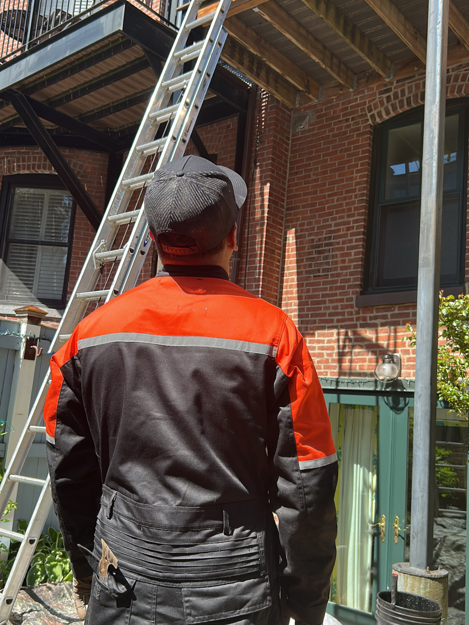 Construction worker facing ladder by brick building