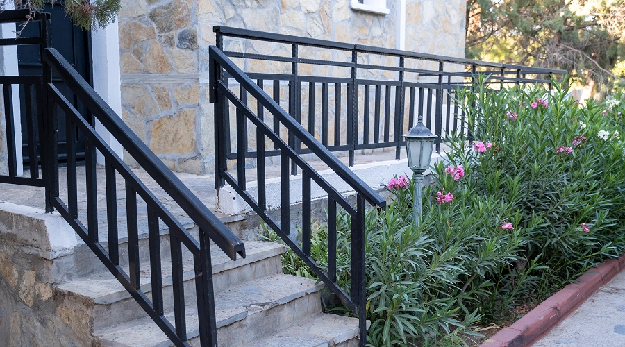 Stone steps with black railings and flowers.