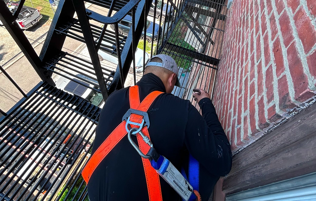 Worker wearing safety harness on fire escape.