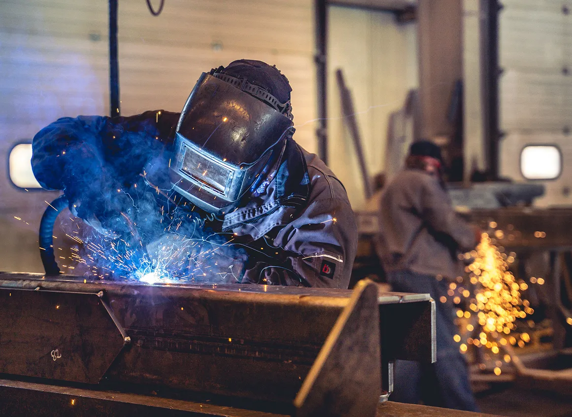 Welder working with sparks in workshop.