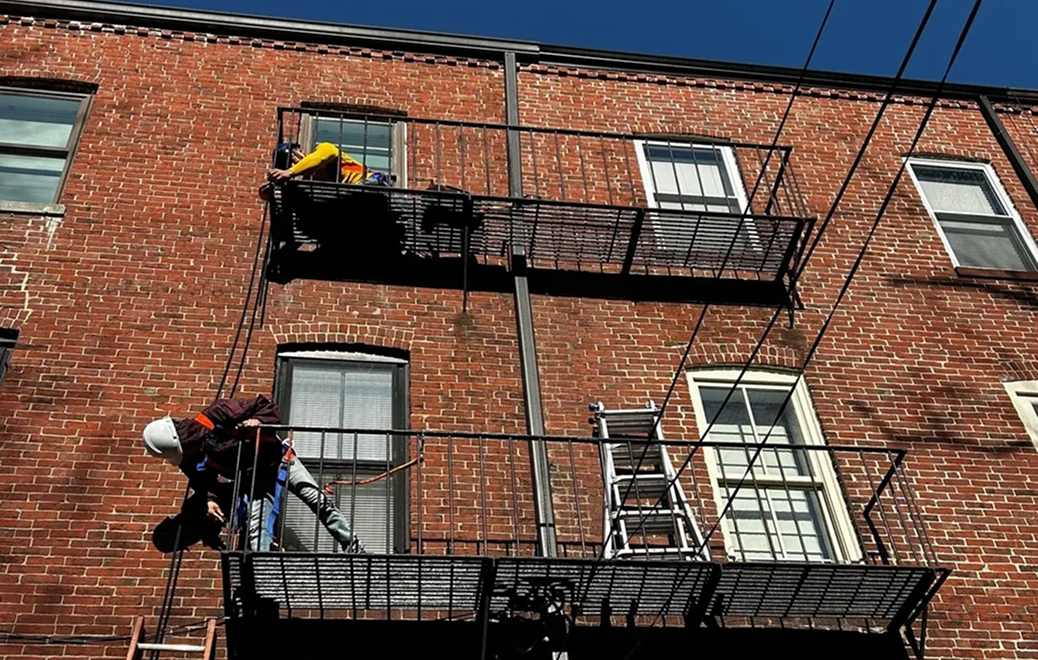 Workers repairing building fire escape ladders.