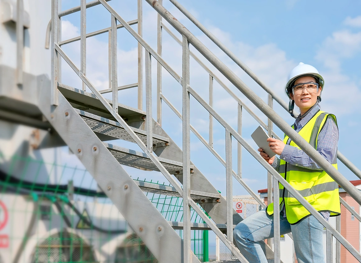 Construction worker on stairs holding clipboard.
