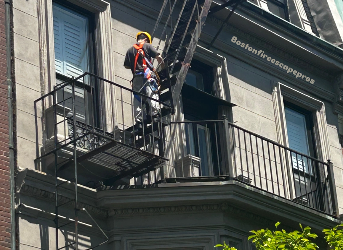 Worker inspecting fire escape on building exterior.